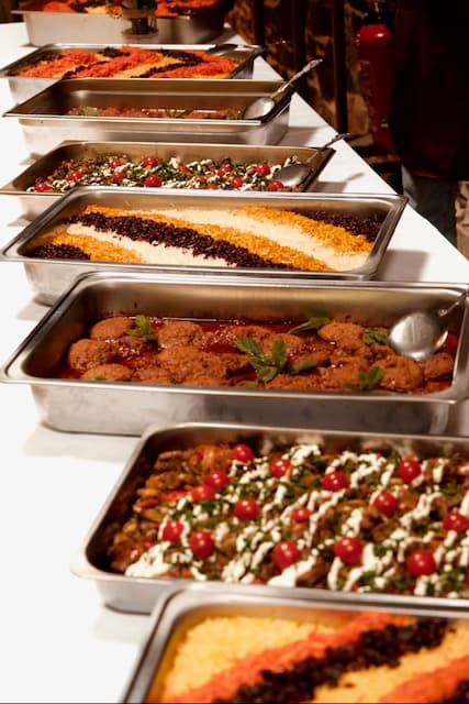 Buffet traiteur : plateaux de riz, plats mijotés et garnitures disposés en ligne
